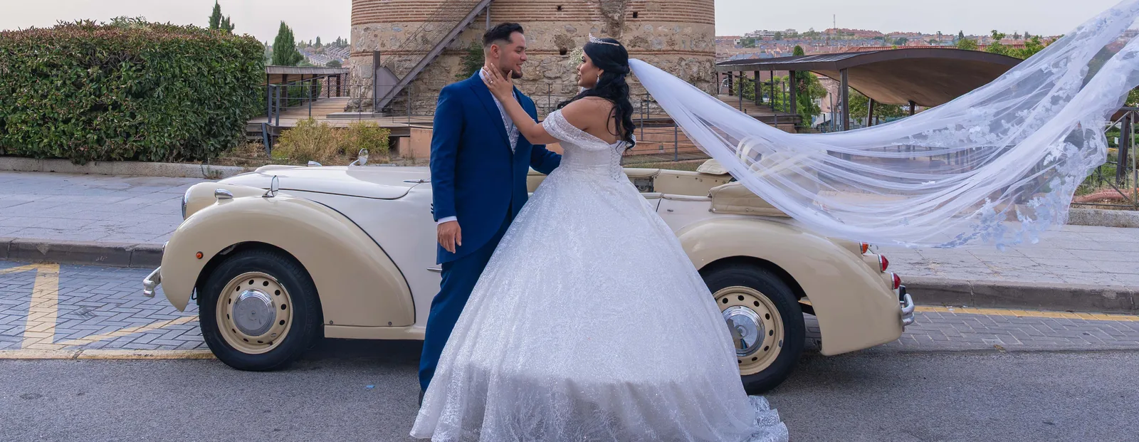 Pareja de novios junto a coche clásico en Madrid, reportaje de boda