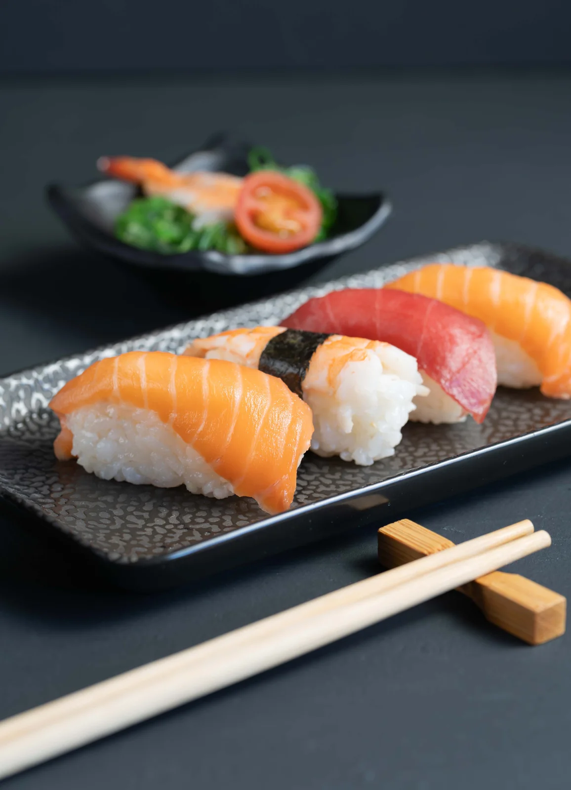Nigiris con palillos en plato oscuro — fotografía gastronómica japonesa en Madrid — Roberto Romero